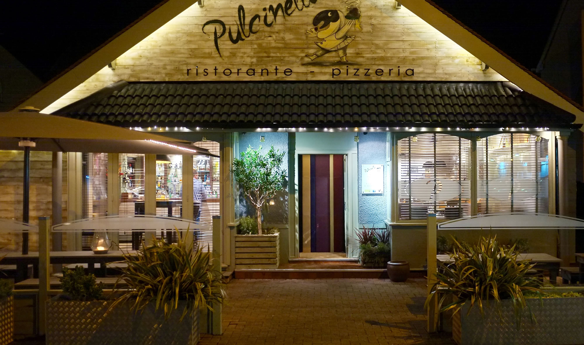 Pulcinella illuminated storefront and entrance at night