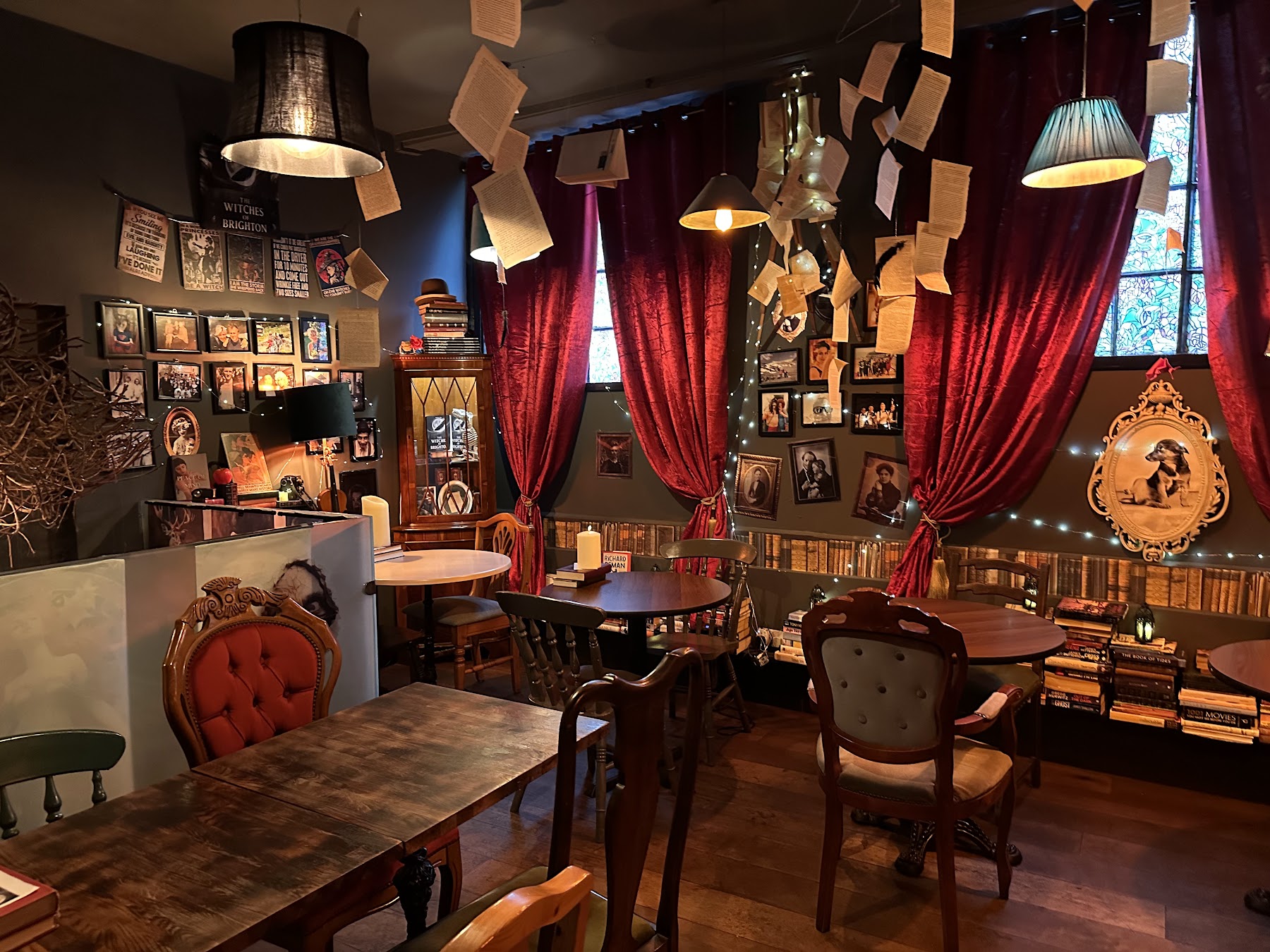 Dining room with arched leaded windows, candles and book pages suspended from the ceiling
